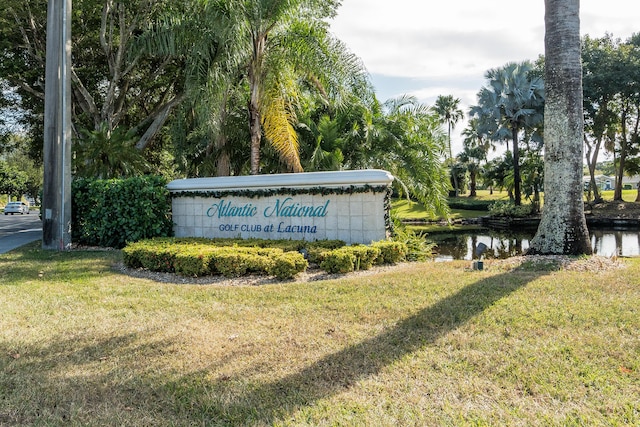 community / neighborhood sign featuring a water view and a lawn