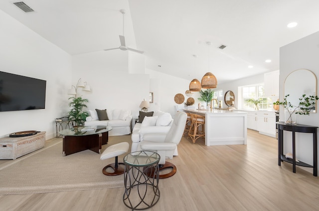 living room with ceiling fan, light hardwood / wood-style floors, and lofted ceiling