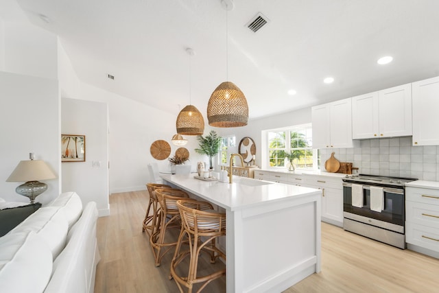 kitchen featuring white cabinets, stainless steel electric range, light wood-type flooring, and hanging light fixtures