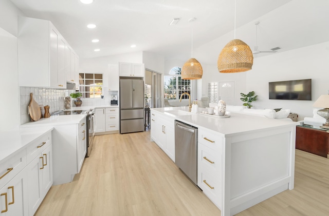 kitchen featuring appliances with stainless steel finishes, a kitchen island with sink, sink, white cabinetry, and hanging light fixtures