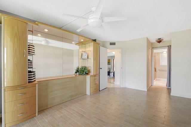 interior space with ceiling fan, light wood-type flooring, and a textured ceiling