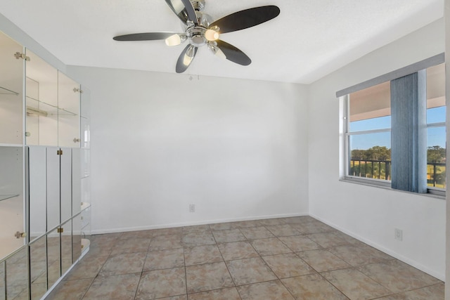 tiled spare room with ceiling fan