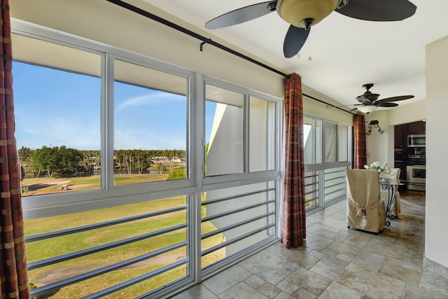 unfurnished sunroom featuring ceiling fan