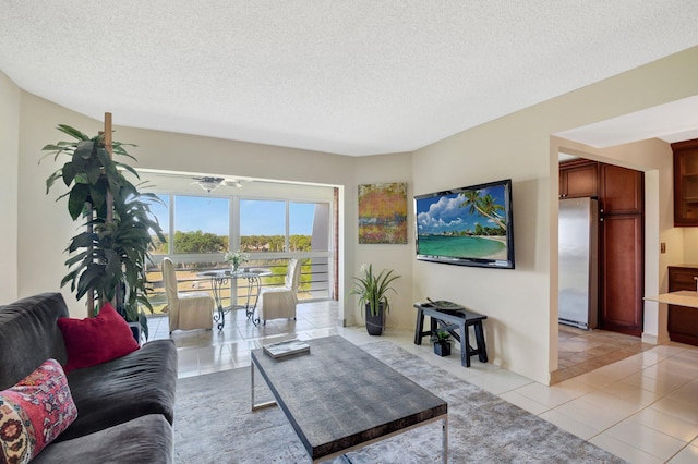 living room featuring ceiling fan, light tile patterned flooring, and a textured ceiling