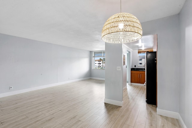 unfurnished room featuring a notable chandelier and light hardwood / wood-style flooring