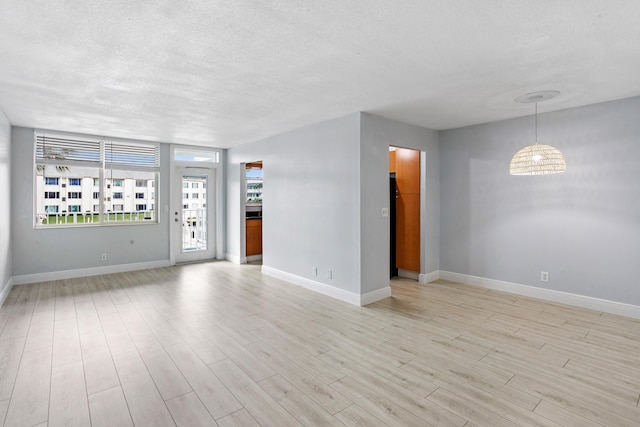 unfurnished room featuring a textured ceiling and light wood-type flooring