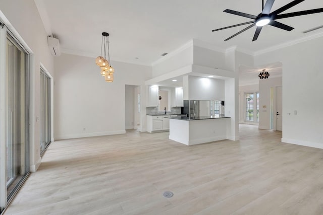 kitchen with an AC wall unit, white cabinetry, hanging light fixtures, and light wood-type flooring