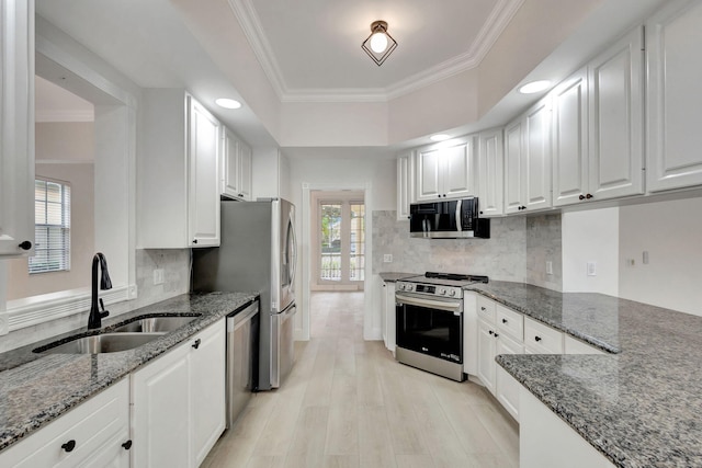 kitchen featuring sink, light hardwood / wood-style flooring, dark stone countertops, white cabinets, and appliances with stainless steel finishes