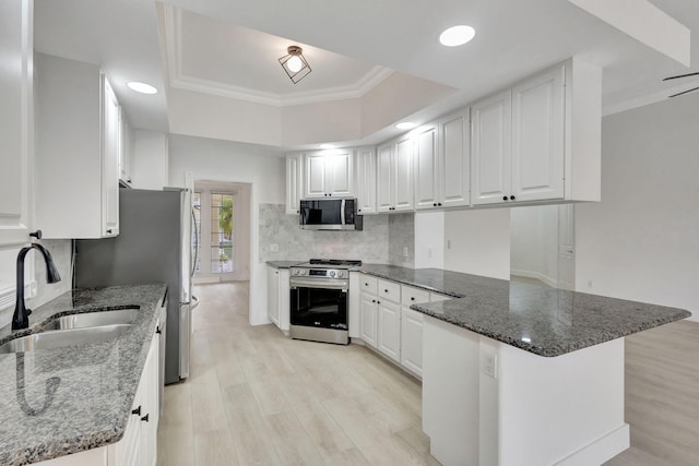 kitchen featuring kitchen peninsula, appliances with stainless steel finishes, light wood-type flooring, sink, and white cabinets