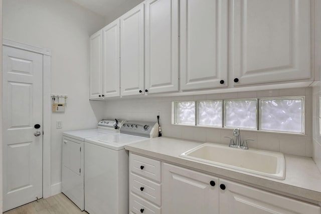 laundry area with separate washer and dryer, sink, cabinets, and light hardwood / wood-style floors