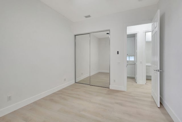 unfurnished bedroom with light hardwood / wood-style flooring and a closet