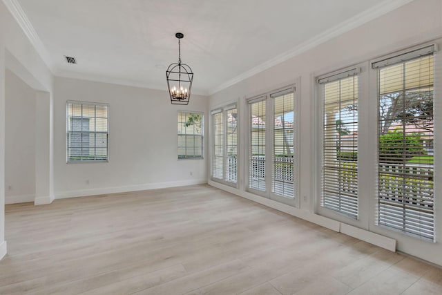 spare room with light hardwood / wood-style flooring, ornamental molding, and an inviting chandelier