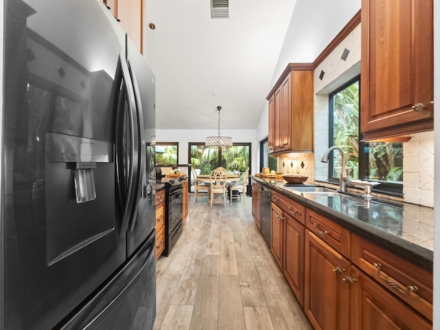 kitchen featuring a healthy amount of sunlight, black appliances, decorative light fixtures, and light hardwood / wood-style floors