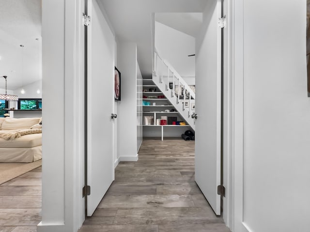 corridor with light hardwood / wood-style floors and lofted ceiling