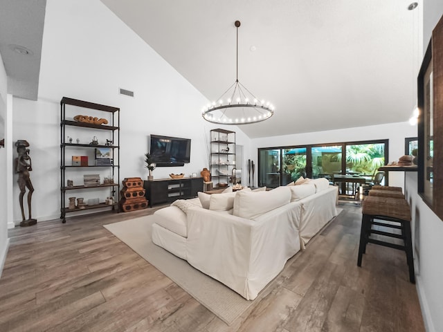 living room with hardwood / wood-style floors, high vaulted ceiling, and a chandelier