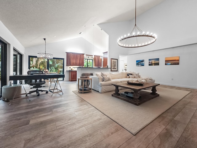 living room featuring a textured ceiling, high vaulted ceiling, hardwood / wood-style flooring, and an inviting chandelier