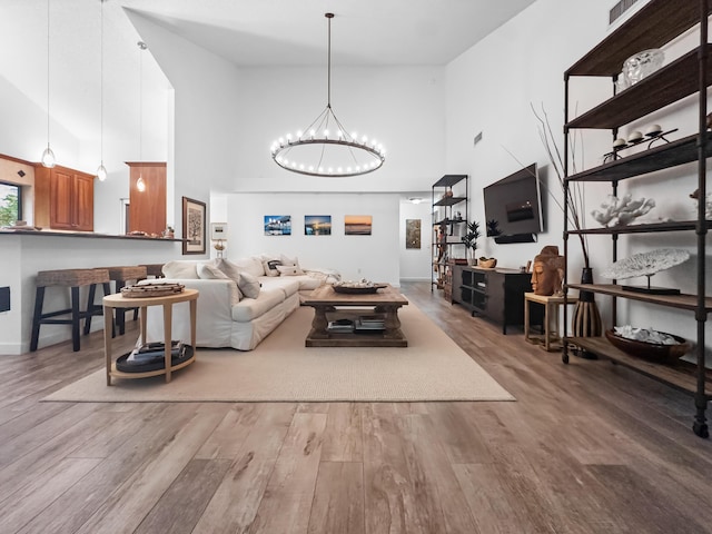 living room with a chandelier, hardwood / wood-style floors, and a towering ceiling