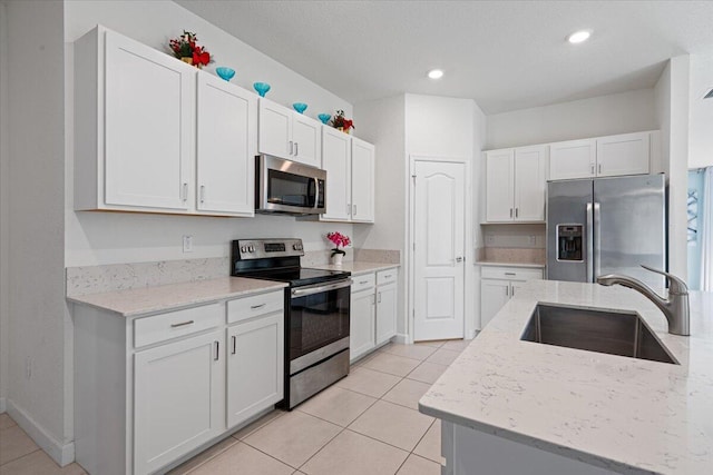 kitchen featuring light stone counters, stainless steel appliances, white cabinetry, and sink