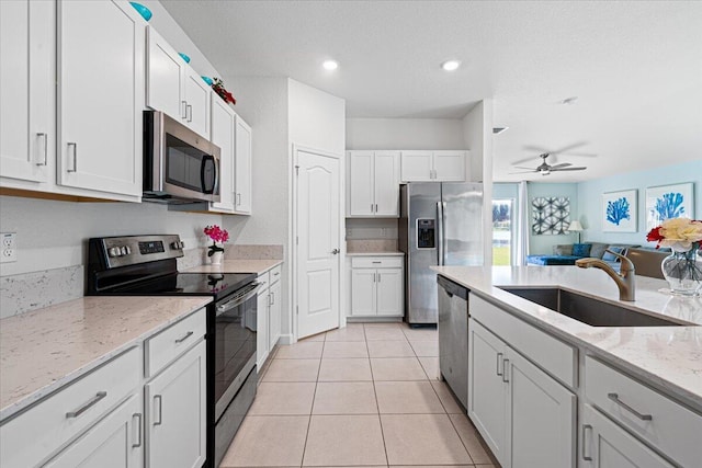 kitchen with stainless steel appliances, white cabinetry, ceiling fan, and sink