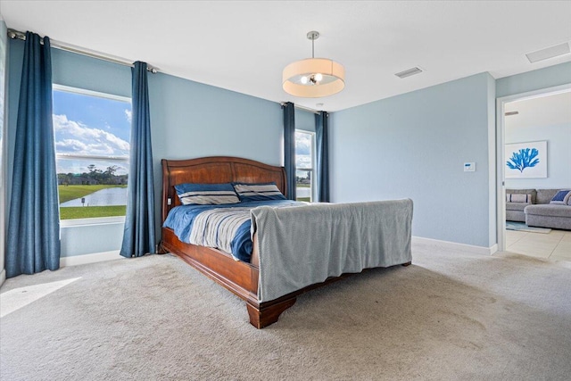 bedroom with a water view and light colored carpet