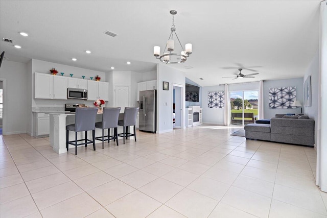 kitchen with white cabinetry, hanging light fixtures, stainless steel appliances, a kitchen breakfast bar, and a kitchen island