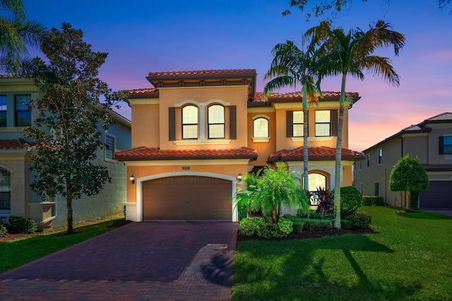 mediterranean / spanish house featuring a garage and a yard