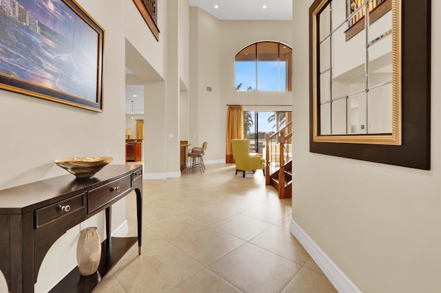 hall with light tile patterned flooring and a high ceiling