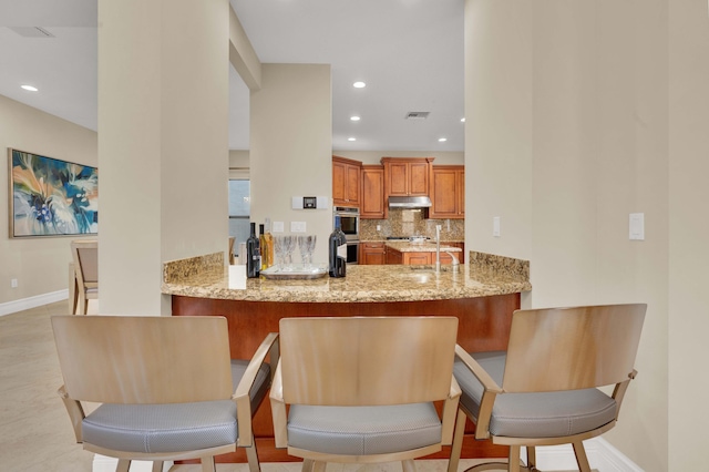 kitchen featuring light stone countertops, sink, double oven, and tasteful backsplash