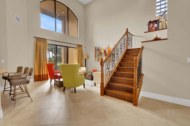 dining area with a towering ceiling and light tile patterned flooring