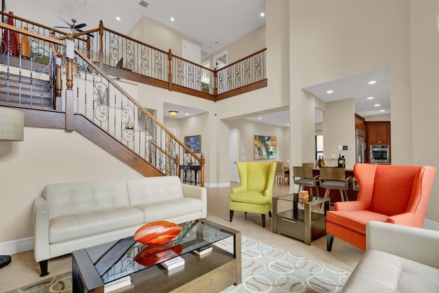 carpeted living room with ceiling fan and a towering ceiling