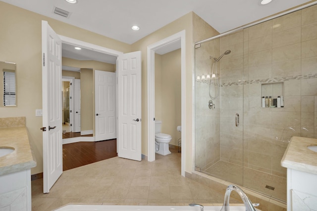 bathroom featuring wood-type flooring, vanity, toilet, and walk in shower