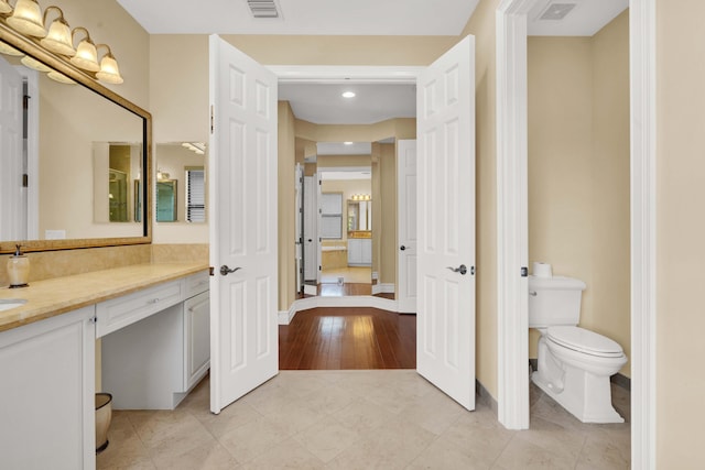 bathroom with hardwood / wood-style floors, vanity, and toilet