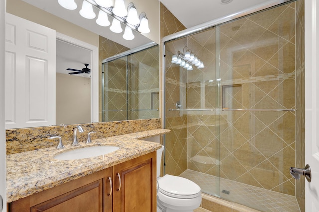 bathroom with ceiling fan, vanity, an enclosed shower, and toilet