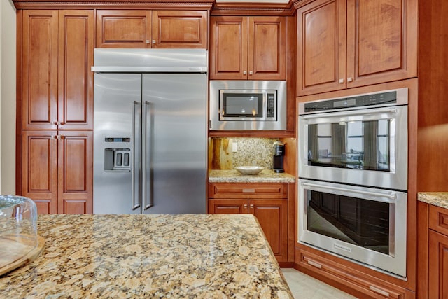 kitchen with light stone countertops, built in appliances, and backsplash