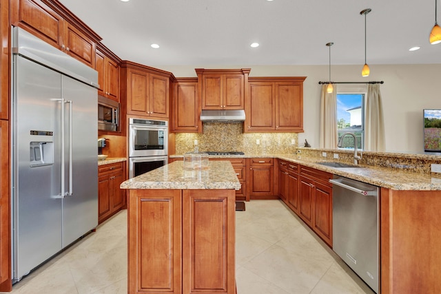 kitchen with sink, built in appliances, decorative light fixtures, a kitchen island, and light stone counters