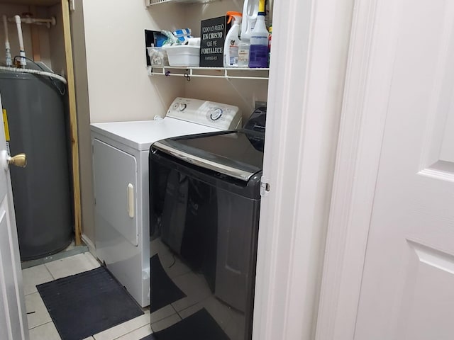 laundry area with independent washer and dryer, light tile patterned floors, and water heater