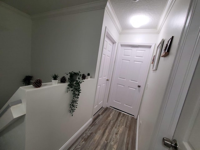 hall featuring hardwood / wood-style flooring, ornamental molding, and a textured ceiling