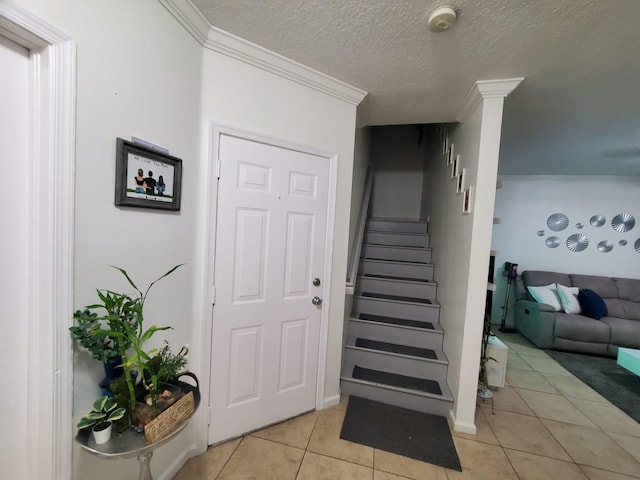 stairway featuring tile patterned flooring, a textured ceiling, and ornamental molding