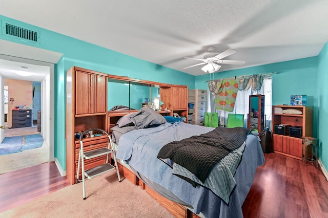 bedroom featuring ceiling fan, dark hardwood / wood-style flooring, and a textured ceiling