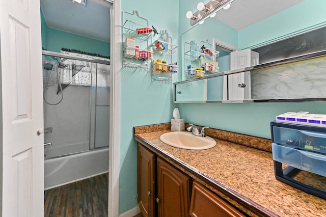 bathroom featuring wood-type flooring, vanity, and enclosed tub / shower combo