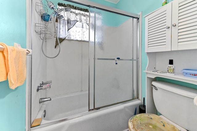 bathroom featuring toilet and bath / shower combo with glass door