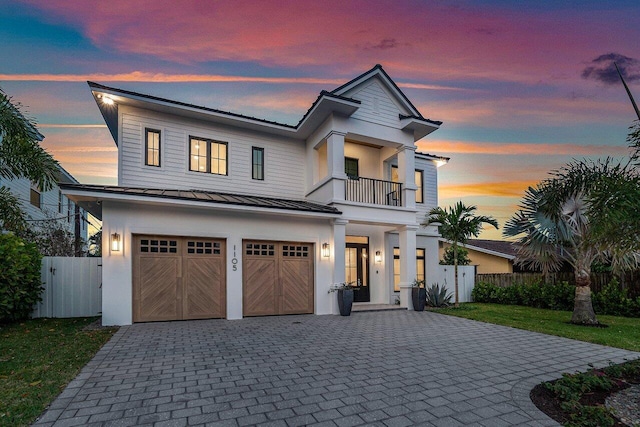 view of front of house featuring a balcony, a garage, and a lawn