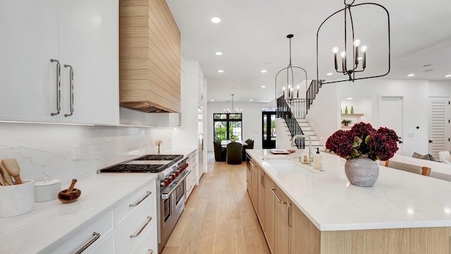 kitchen with light stone countertops, hanging light fixtures, a spacious island, and range with two ovens