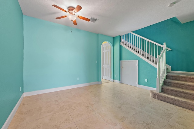 tiled empty room with ceiling fan and a textured ceiling