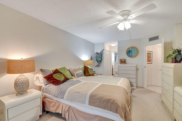 bedroom featuring ceiling fan, light colored carpet, and a textured ceiling