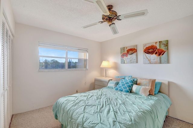 carpeted bedroom featuring ceiling fan, a closet, and a textured ceiling