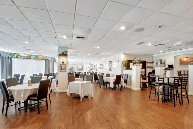 dining space with hardwood / wood-style flooring and a paneled ceiling