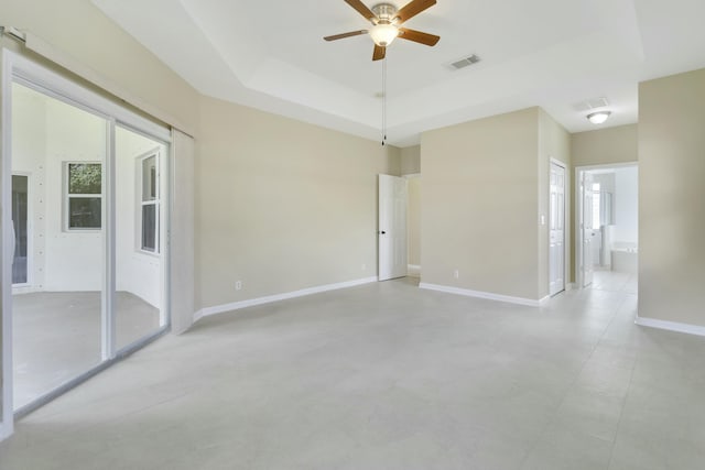 spare room with ceiling fan and a tray ceiling