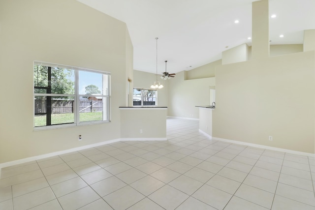 tiled spare room featuring ceiling fan with notable chandelier and high vaulted ceiling