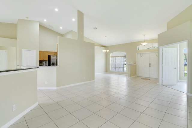 unfurnished living room with high vaulted ceiling, light tile patterned flooring, a wealth of natural light, and a chandelier